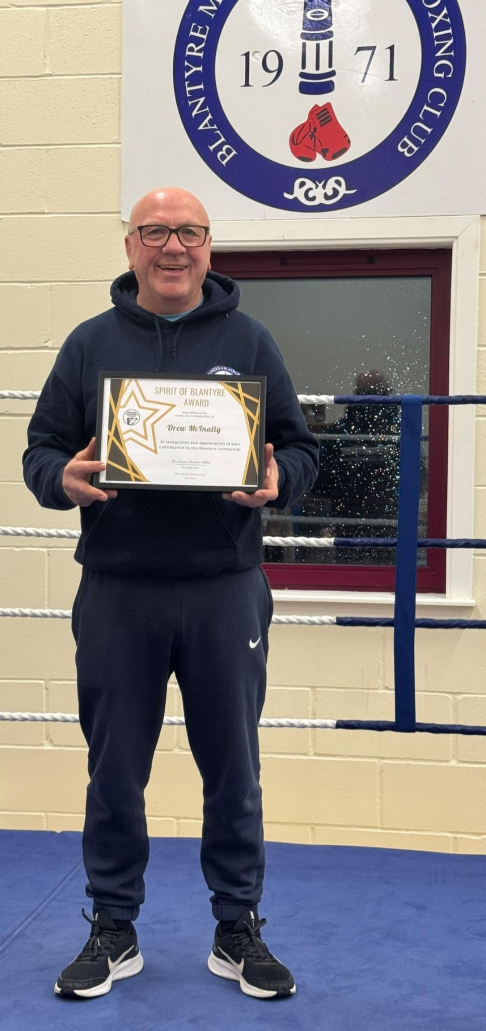 Drew McInally holding his Spirit of Blantyre certificate at the boxing club